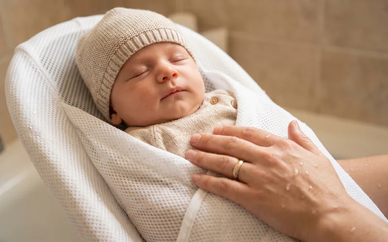 Newborn baby reclining peacefully in soft touch Angelcare baby bath mesh support