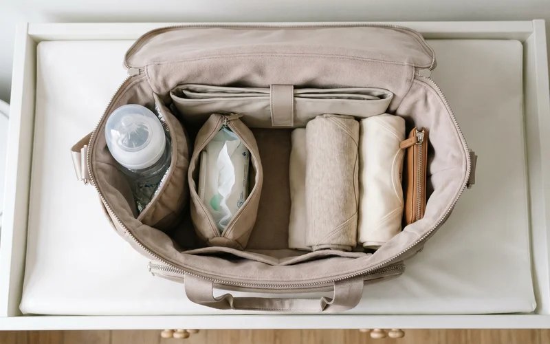 Inside of a baby changing bag showing insulated bottle pocket, wipes pouch, changing mat and spare babygrows